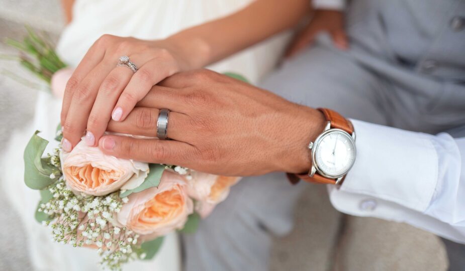 Hände mit Ringen auf einem Brautstrauß