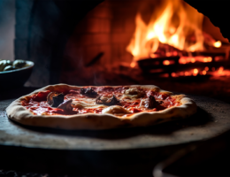 Pizza vor einem Holzofen der mit einem Feuer beheizt wird