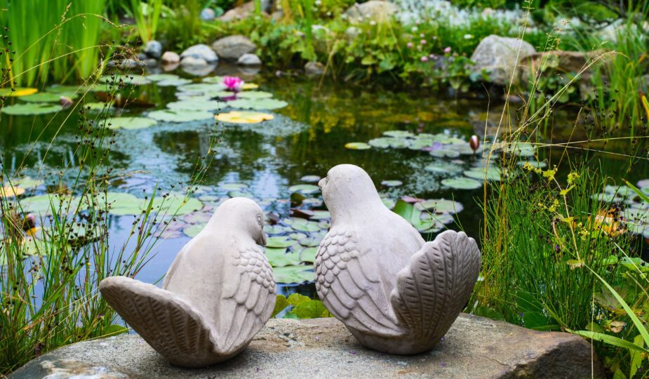 Ein paar Vögel - Gartenskulptur vor einem Teich