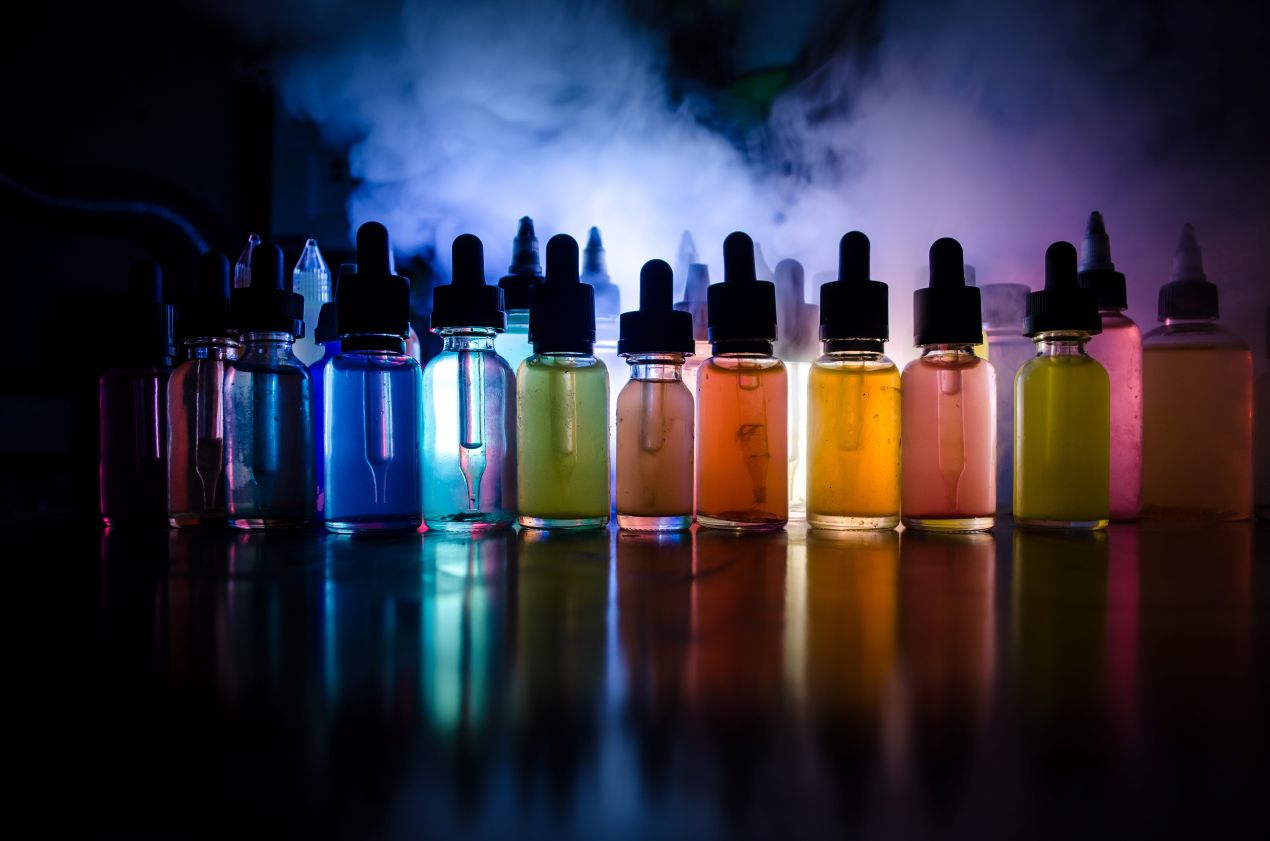 Leuchtende Liquidfläschchen in verschiedenen Farben im Gegenlicht – Symbolbild für die Geschmacksvielfalt von Elfbar Liquids