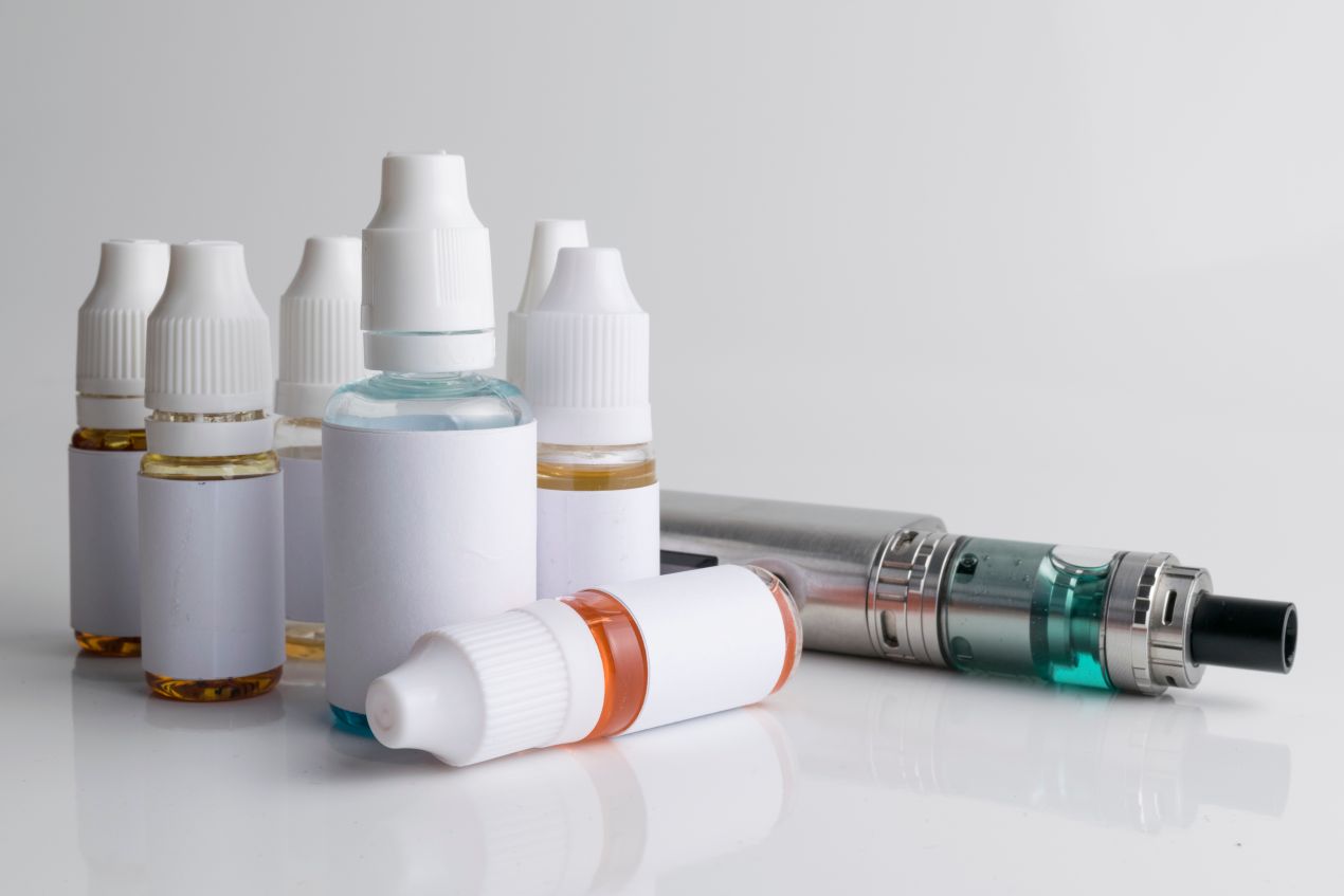 Mehrere ungekennzeichnete Liquid-Flaschen mit E-Zigarette auf weißem Hintergrund – Symbolbild für Lagerung von Elfbar Liquids