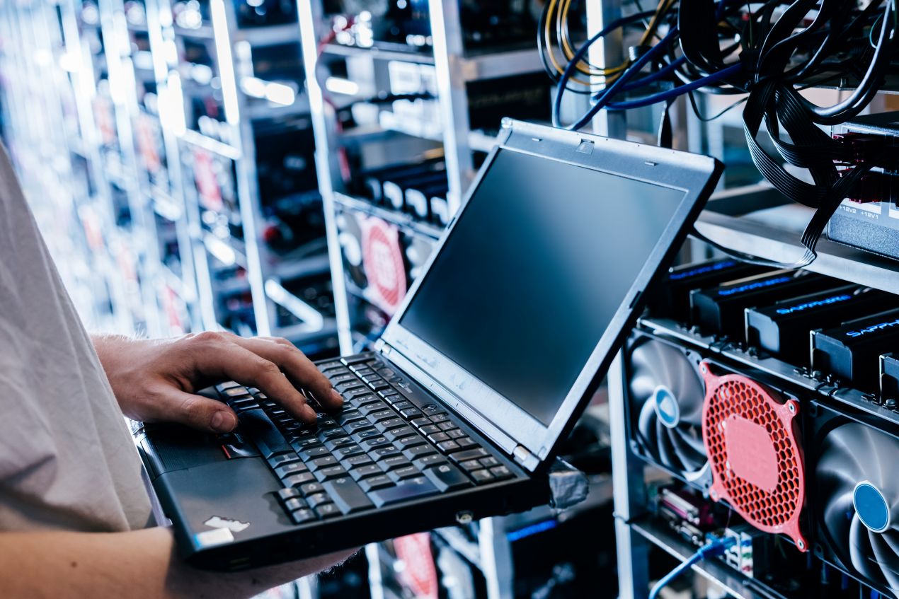Techniker konfiguriert Netzwerkkomponenten mit Laptop – praxisnahes Beispiel fuer den Einsatz von Singlemode-Verbindungen im Serverraum
