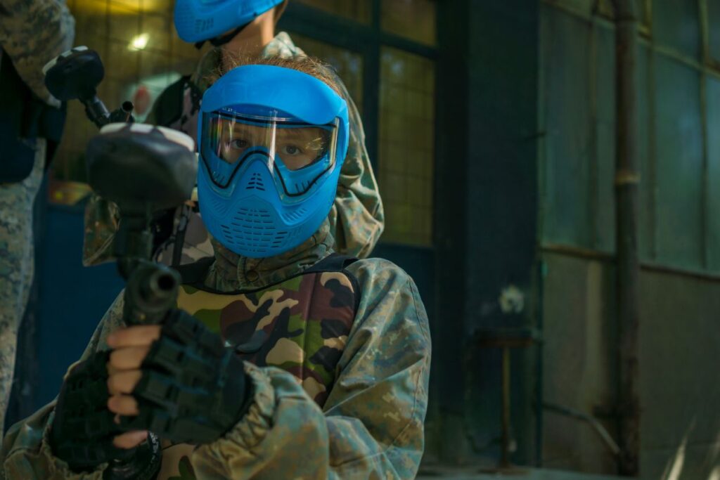 Person mit blauer Schutzmaske haelt Paintball Waffe bereit fuer erstes Match